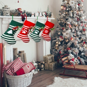 Detailed knit Christmas socks for cats and dogs hanging on a white fireplace mantle