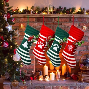 Close-up of four knitted Christmas pet socks with festive pine needles and berry details