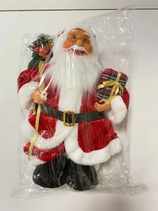 Detail of Santa Claus plush in red suit holding gift box and green bag decoration