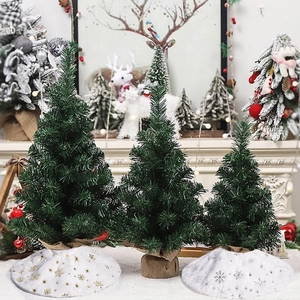Three mini green Christmas trees with gold and silver snowflake patterned tree skirts