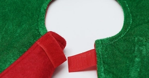 Detail of red and green velvet Christmas tree skirt featuring secure hook and loop fastener
