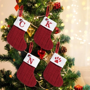 Set di quattro calze di Natale rosse in maglia a trecce appese a un albero decorato