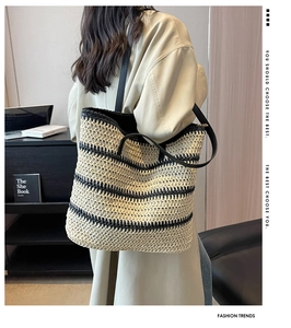 Detailed close-up of handmade woven texture and black leather strap on a striped tote bag