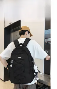 Vue latérale du grand sac à dos noir en nylon avec pendentif panda porté par l'étudiante
