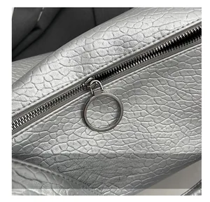 Detail of silver-grey pebbled leather bag with smooth black zipper and metal ring pull