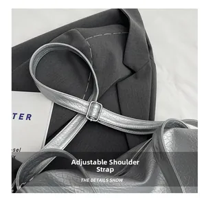 Detail show of silver textured leather bag with adjustable shoulder strap and metal buckle