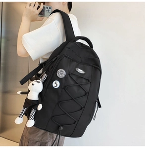 Détail d'un sac à dos en nylon noir avec charm lapin à carreaux et écusson tigre