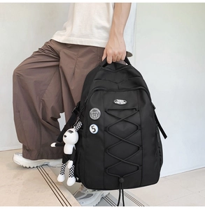 Détail d'un sac à dos en nylon avec cordons croisés, badges et un charme à damier