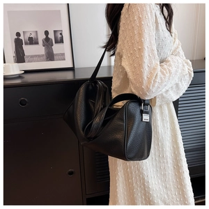 Detail of black textured leather boston bag showing wide strap and silver metal buckle
