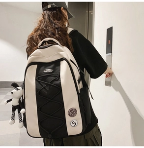 Gros plan du sac à dos en nylon noir et blanc avec cordons décoratifs et breloque poupée rayée