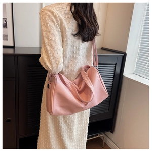Detailed view of a pink pebbled leather hobo bag worn by a model in white dress