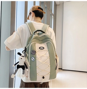 Détail d'un sac à dos en nylon vert avec badges décoratifs et peluche lapin à carreaux