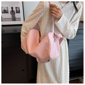 Pink pebbled leather shoulder bag shown on model with wide strap and silver buckle detail