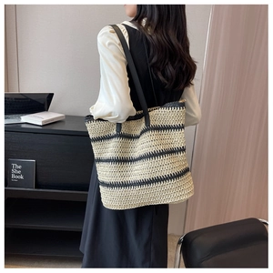Detail of a large woven tote bag featuring black and beige stripes with slim leather straps