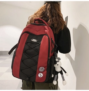 Détail arrière du sac à dos en nylon rouge et noir avec pendentif de poupée décorative