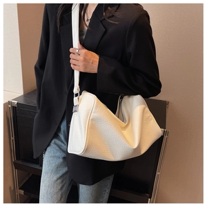 Detail view of large white leather shoulder bag with textured finish and wide strap