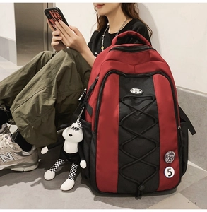 Détail du sac à dos en nylon rouge et noir avec cordons élastiques et pendentif poupée