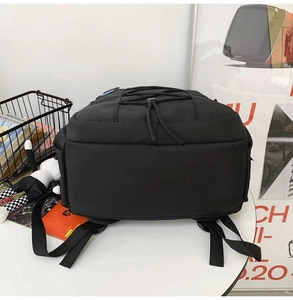 Vue arrière du sac à dos en nylon noir avec cordon de serrage sur une table blanche pure