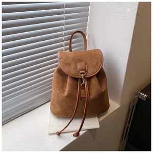 Close-up of brown suede backpack featuring a drawstring closure and vintage metal hook