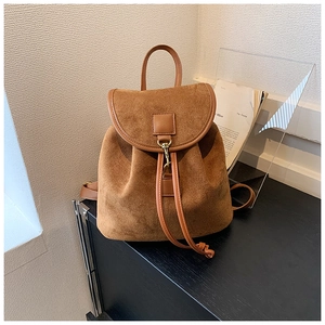 Detailed close-up of brown suede backpack with flip-top lid and golden metal lock