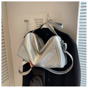 Detailed view of silver metallic textured pillow bag on a black blazer for office styling