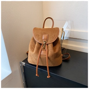Detail of brown frosted leather backpack showing drawstring closure and bronze metal buckle