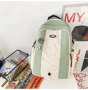 Détail du sac à dos en nylon vert clair et beige avec cordons et badges mignons