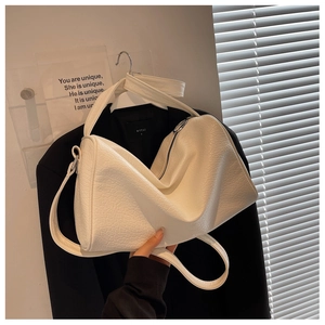 Detail of a white textured large shoulder bag with zipper and dual straps on black blazer