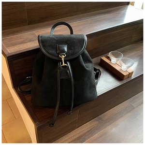 Detail of black suede backpack featuring leather trim and golden metal hook on steps