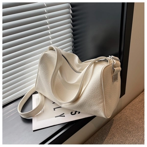 Detail of cream white cylinder bag with pebbled leather texture and silver zipper