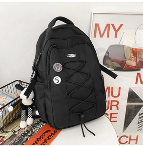 Détail d'un sac à dos en nylon noir avec cordons élastiques et badges décoratifs
