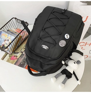 Détail d'un sac à dos noir en nylon avec cordons élastiques et badges sportifs ronds