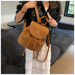 Detail view of a vintage brown suede backpack with metal hook and drawstring closure