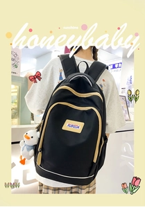Detail of a black nylon backpack with beige piping and a cute duck plush keychain