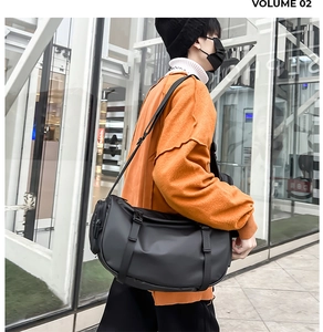 Detail of a black large capacity crossbody travel bag with buckle strap on a model
