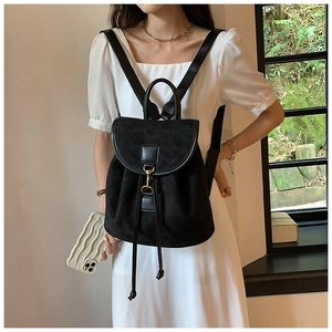 Close-up of matte black leather backpack featuring gold buckle and drawstring closure