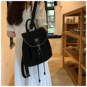 Detail of black matte backpack featuring premium leather flap and gold metal hardware