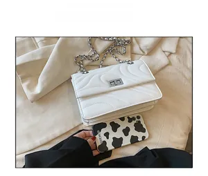 Comparaison de taille d'un sac bandoulière blanc matelassé avec un smartphone moderne