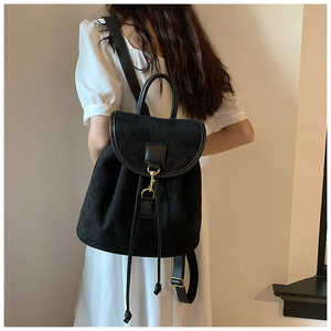 Detail of black frosted backpack with gold hook buckle and flap design on a white dress model