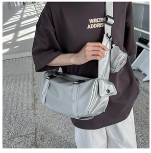 Silver large travel bag with mini pouch shown on shoulder in a minimalist setting