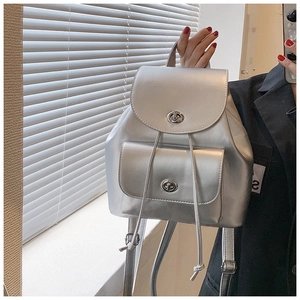 Détail d'un mini sac à dos argenté métallisé avec fermoirs rotatifs et bretelles