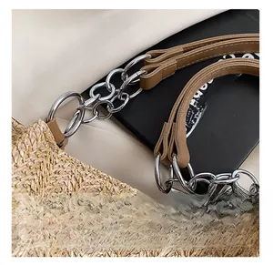 Close-up of woven straw tote bag with silver metal rings and brown leather handle strap