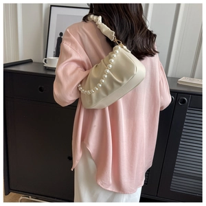 Detail of cream pleated cloud bag featuring pearl chain strap and soft leather texture