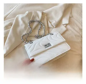 Gros plan du sac en cuir matelassé blanc avec chaîne argentée et fermoir pivotant