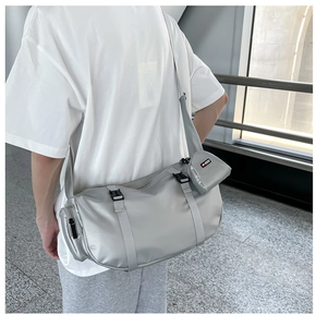 Detail of silver cylindrical crossbody bag featuring a detachable mini coin pouch and strap