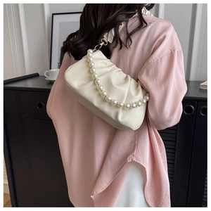 Detail of beige pleated cloud bag with elegant large pearl strap and gold hardware