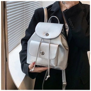 Mini sac à dos argenté avec fermoirs rotatifs sur un blazer noir, vue de profil