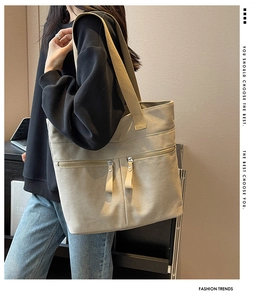 Detail of canvas tote bag showing two front zipper pockets and beige texture