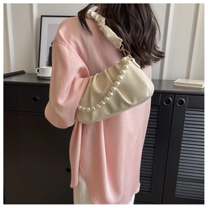 Detail of beige pleated cloud bag with elegant pearl chain and soft texture