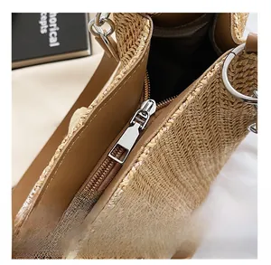 Detail showing the smooth silver metal zipper and brown leather trim on woven straw tote